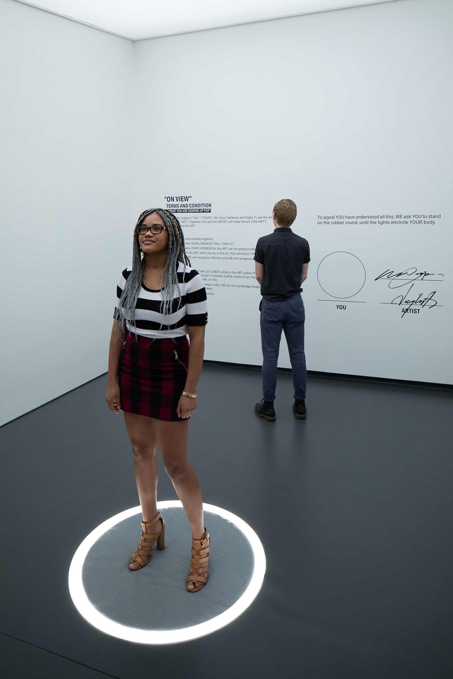 Visitor standing inside a minimalist white interactive exhibition — before retouching